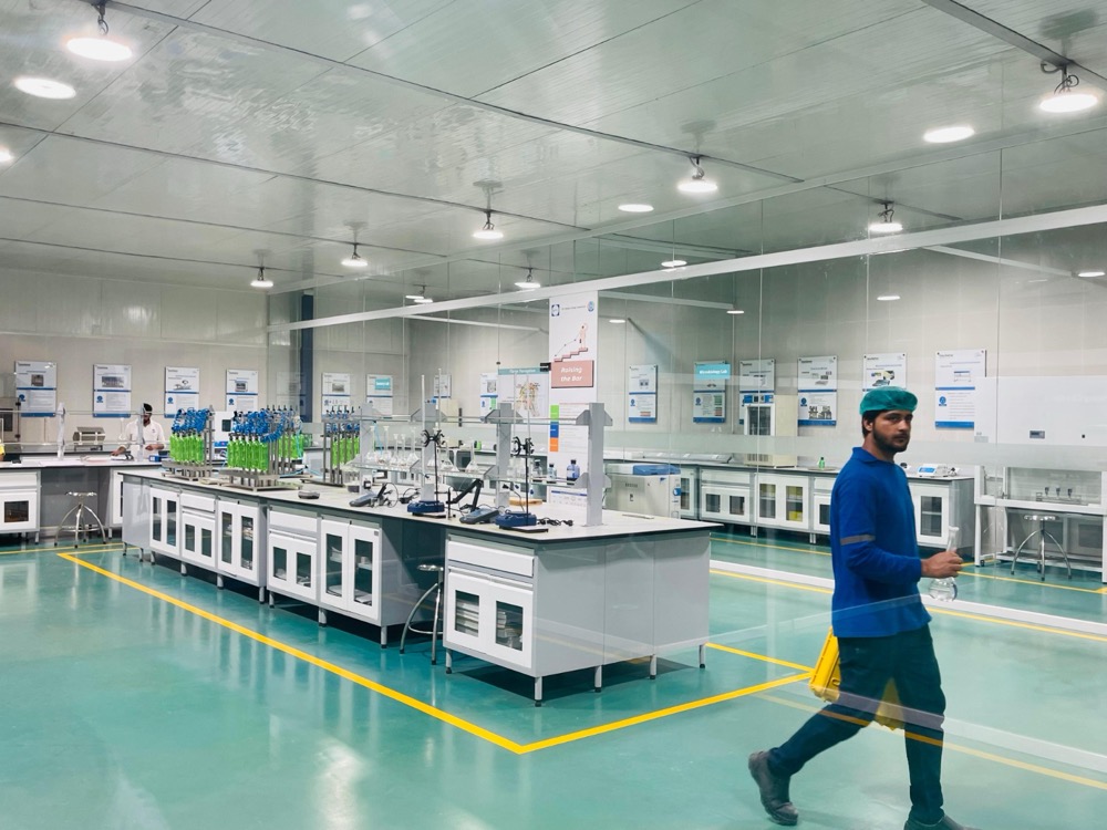 Beverage QC laboratory at Naubahar Bottling Pepsi Gujranwala — central instrument bench with technician at work, PIR-clad walls and ceiling