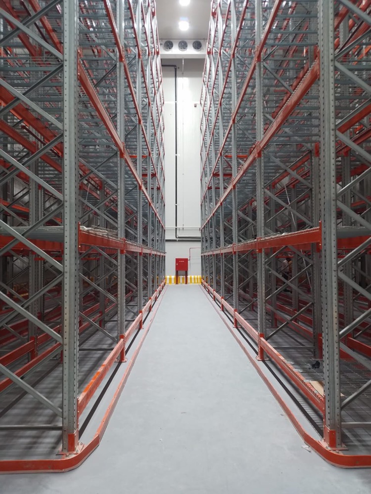 Drive-in pallet racking aisle at Coca-Cola TCCEC Lahore cold storage, with Coca-Cola red rack uprights and Izhar PIR-clad walls