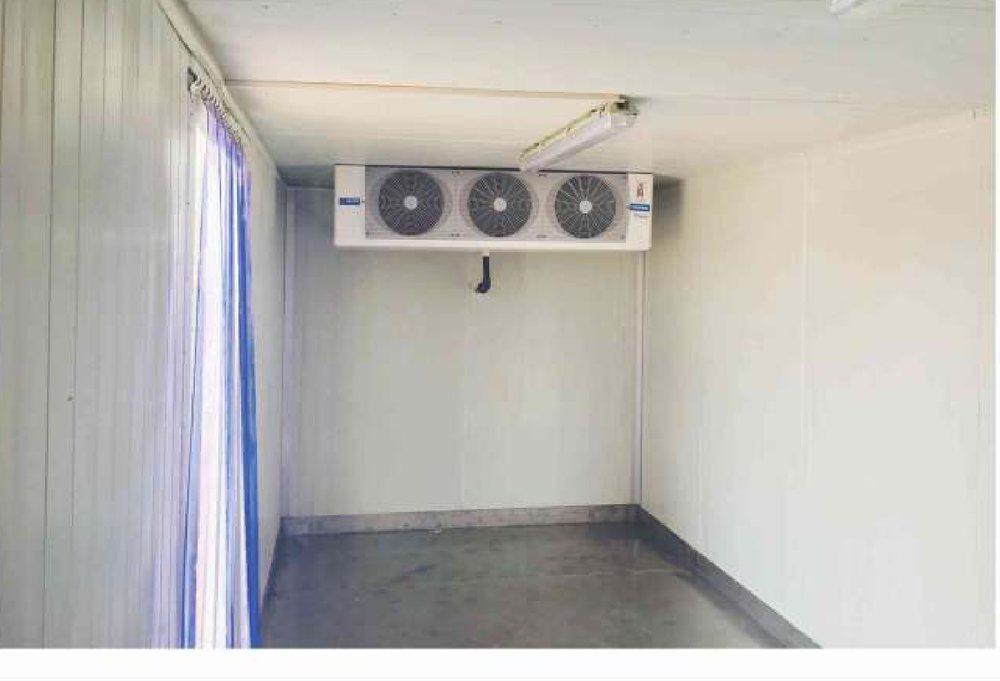 Inside a refrigerated truck body — ceiling-mounted evaporator and PVC strip curtain at the door