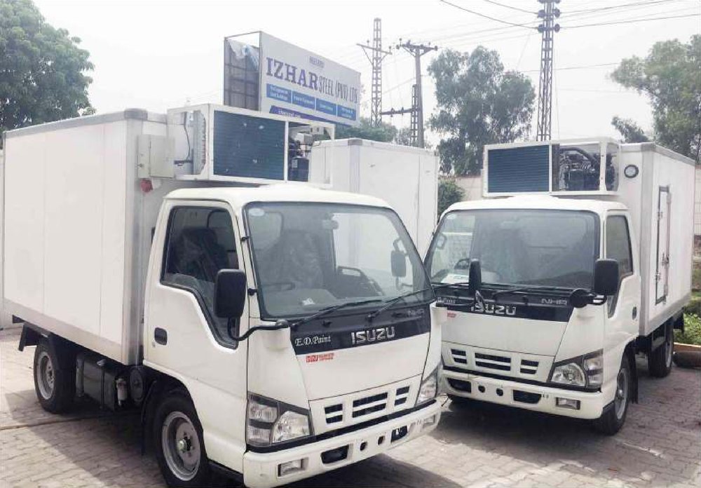 Two completed Izhar Foster refrigerated Isuzu trucks outside the Izhar Steel plant in Lahore